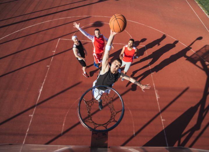 guy jumping to reach basketball hoop