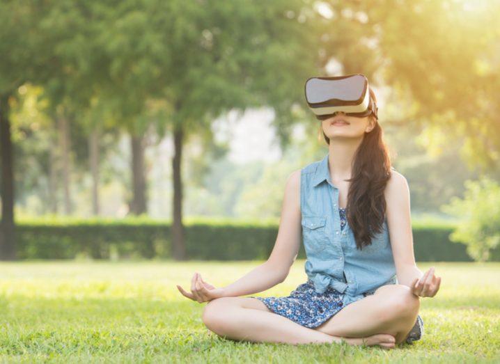 woman meditating in garden with vr headset