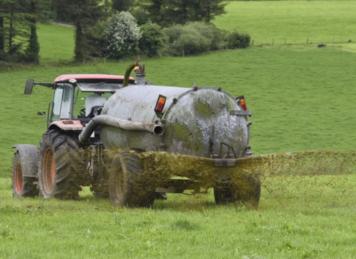 tractor spreading slurry in green field.