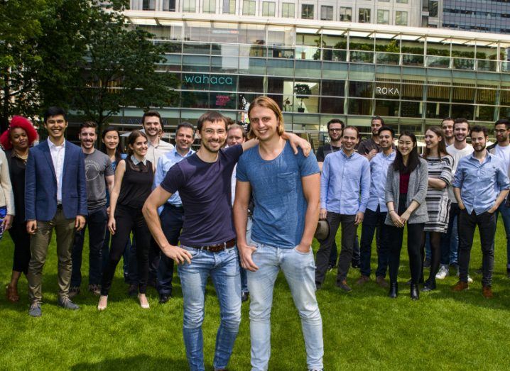 Revolut co-founders stand in front of a large team of people in a park.