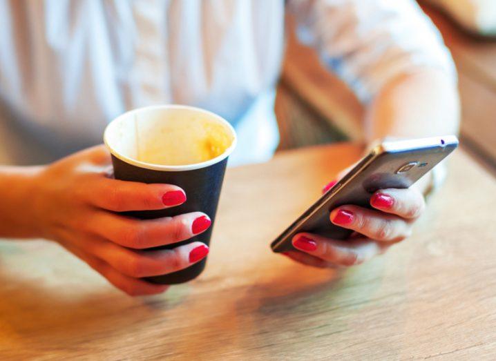 Person using smartphone having coffee