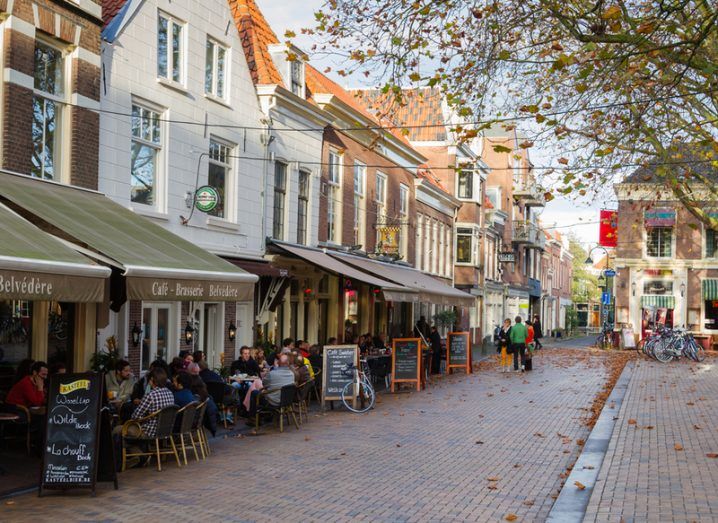 People sitting at an outdoors restaurant in the main square of Delft, the Netherlands.