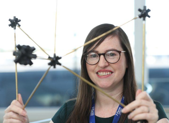 Woman with glasses holding up 3D printed prototype.