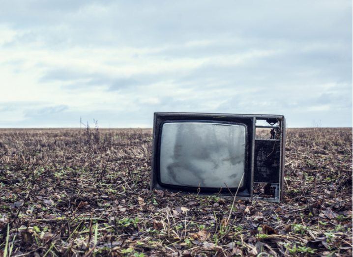 A broken TV in an autumn field.