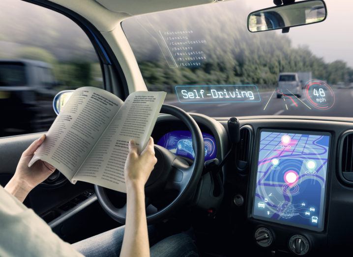 Futuristic image of person reading a magazine while self-driving car takes them on a journey.