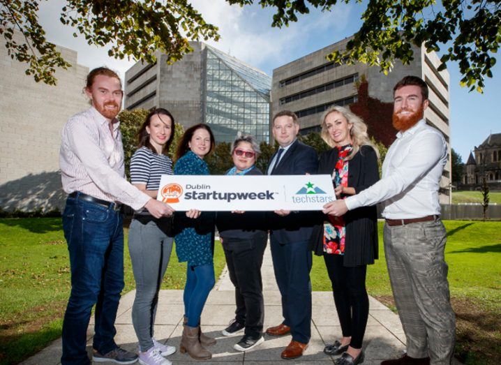 Four women and three men hold a Startup Week Dublin sign in front of Dublin City Council offices.