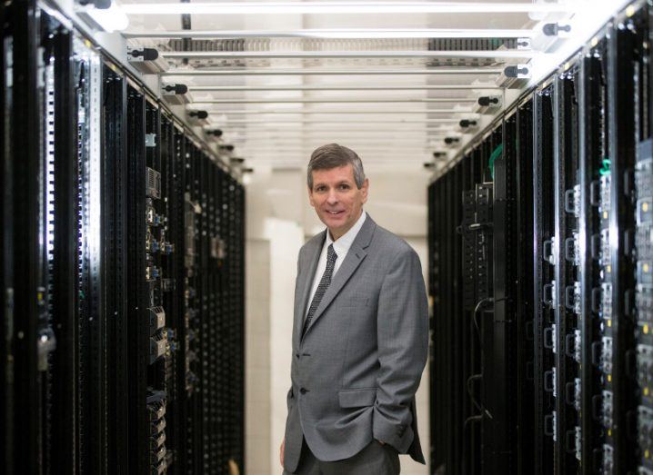 Man in suit stands in data centre hall.