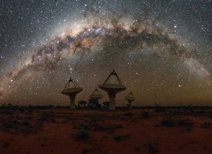 The dish antennas of the radio telescope against a stunning star-filled night sky.