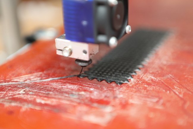 A close-up of a 3D print being constructed layer by layer by extruding the filament from a precise point.