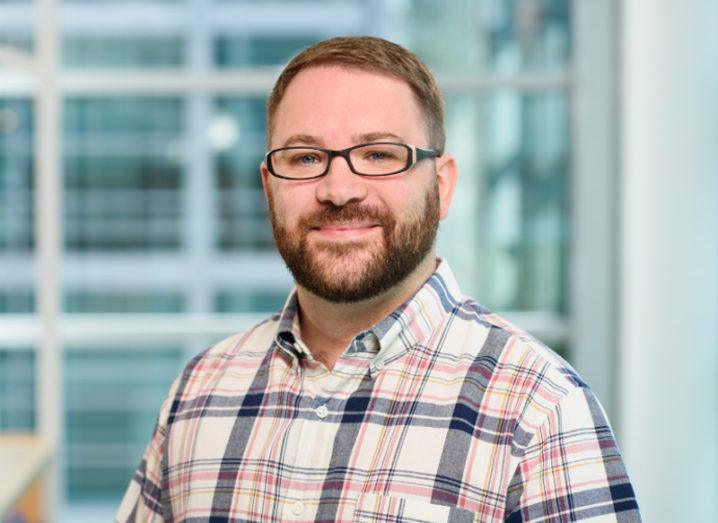 Picture of a man in chequered shirt with beard and glasses.