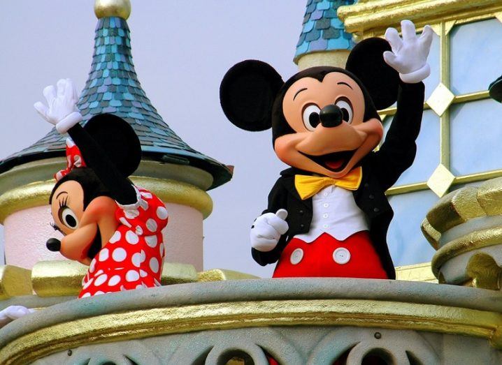 Mickey and Minnie Mouse waving to crowds from the Magic Kingdom castle in Hong Kong.