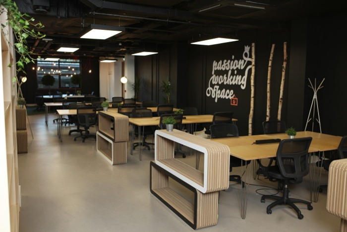 A co-working space in Talent Garden with multiple desks, greenery and soft lighting.