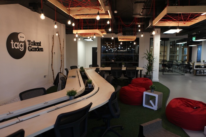 A long desk with multiple chairs with red bean bags around the area.