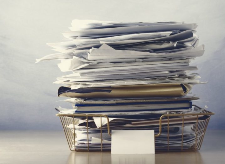 A large pile of files in a wire tray, symbolising an overwhelmed office.