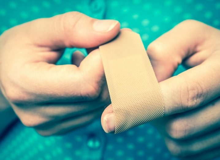 A close-up image of a woman applying a plaster bandage to her finger.