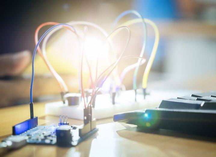 Electronics boards on a wooden table connected to a bright light.