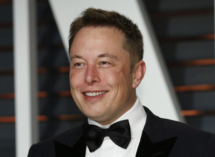 Elon Musk smiling off to the distance while wearing a black tuxedo, white shirt and bow tie.