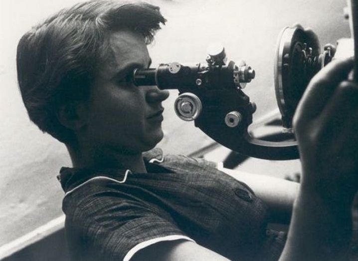 Black and white photo turned sideways of Rosalind Franklin looking through a microscope.