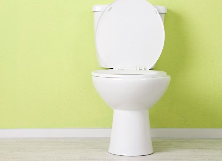 White toilet with open lid against a bright green wall.