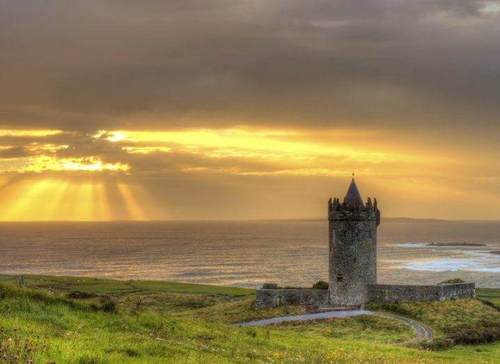 Doonagore Castle, located near the coastal town of Doolin in Co Clare. The sun shines on the sea in the background.