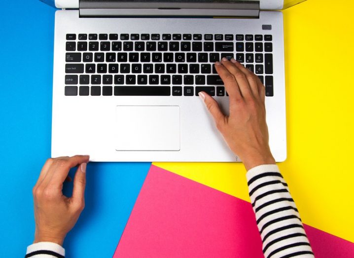 Top-down image of woman using a laptop on colourful background.