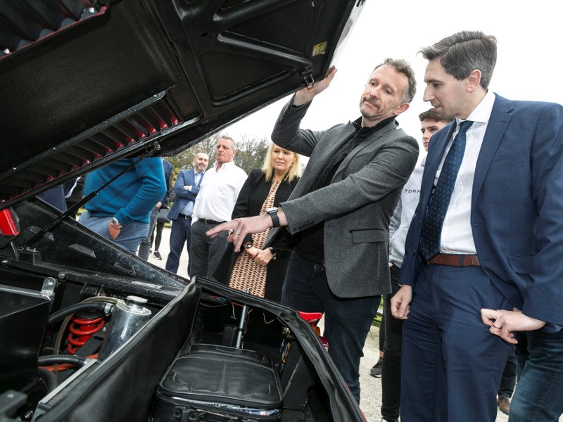 Two men look under the hood of a Ferrari.