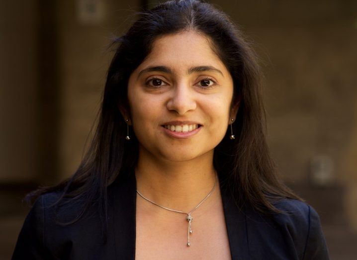 Headshot of RMIT University’s Madhu Bhaskaran smiling while wearing a black blazer against a walled background.