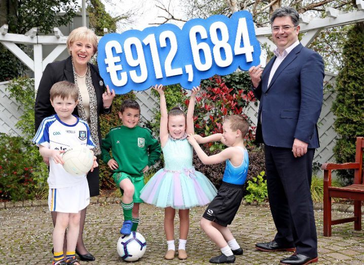 Two adults and four children hold up a sign showing the amount of 912,684 euro.