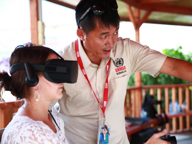 Woman wearing VR headset while an instructor in white shirt explains what she is seeing.