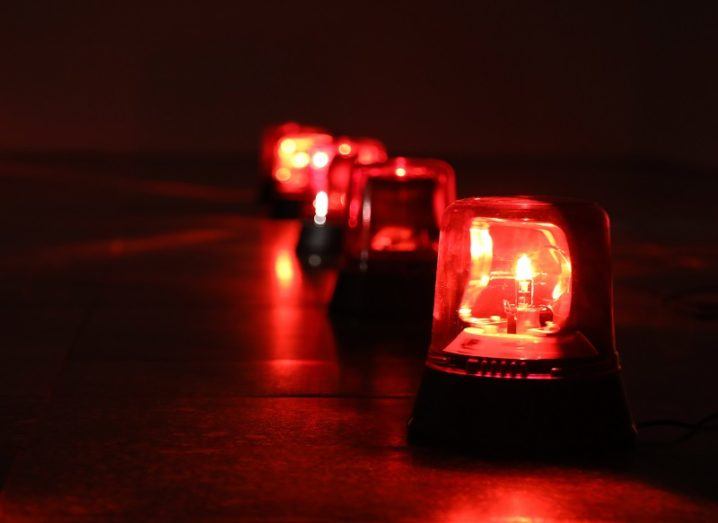 A row of flashing red light alarms in a dark room.