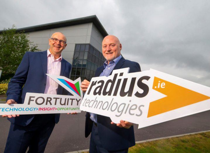 Two men in suits holding signs saying Fortuity and Radius Technologies.