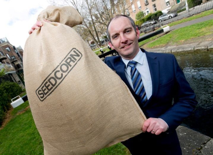 Man holds a Seedcorn bag in front of a canal.