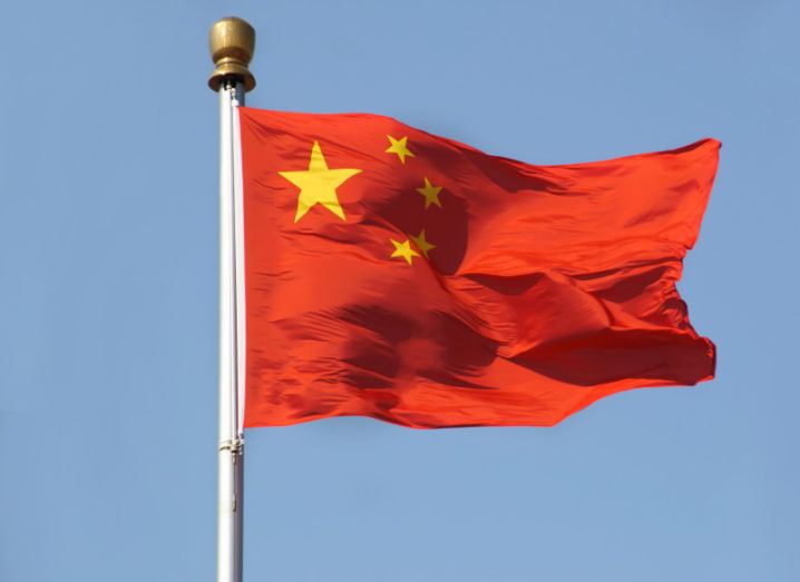 View of Chinese flag against cloudless sky billowing in the breeze.