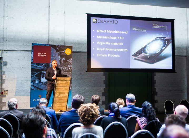 Marcin Kulik stands in front of an audience on a stage presenting his company, Eiravato.