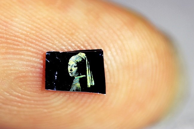 Close-up of a tiny 1mm-wide ‘Girl with a Pearl Earring’ painting on a person's fingertip.