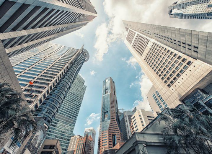 upward shot of grey skyscrapers with cloudy blue sky overhead.