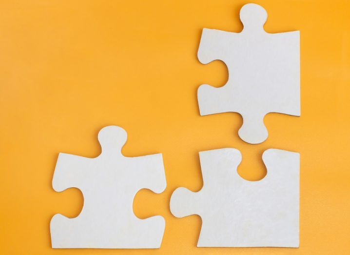 Three white jigsaw pieces separated on an orange background.