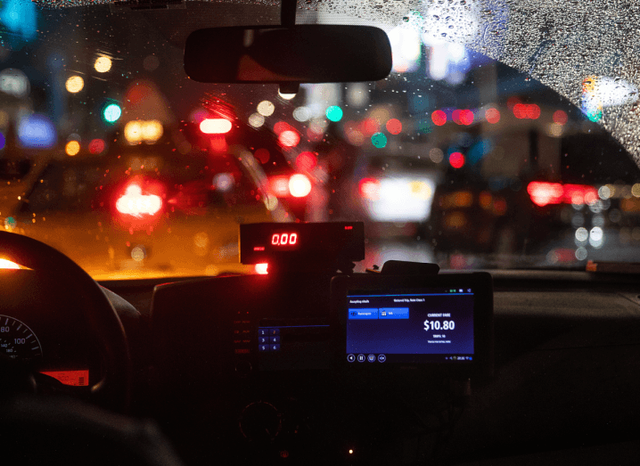 The interior of a taxi on a busy city street at night.