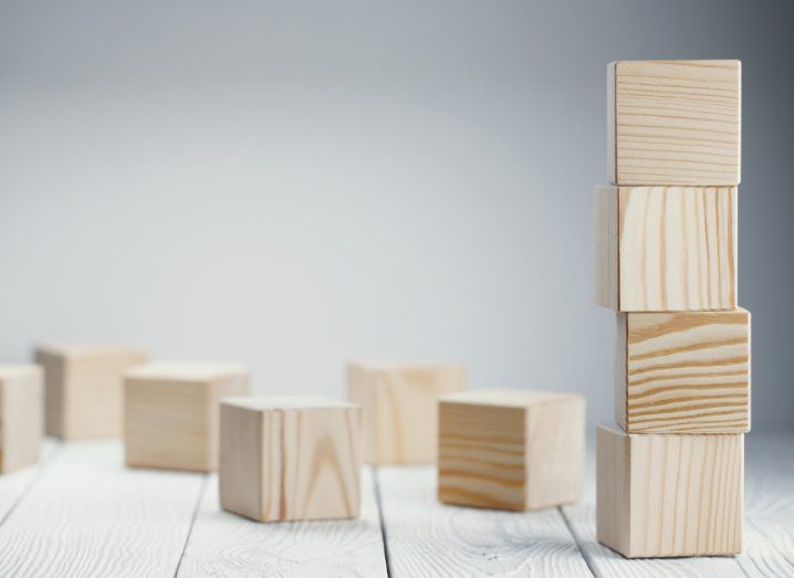 Four wooden blocks piled one on top of the other, surrounded by a scattering of other blocks.