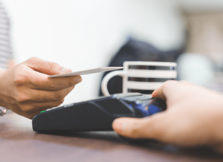 The hand of an individual making a contactless payment with a credit or debit card.