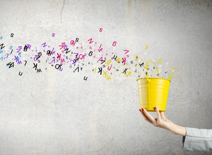 An outreached hand holds a yellow bucket from which a plum of colourful letters are streaming.