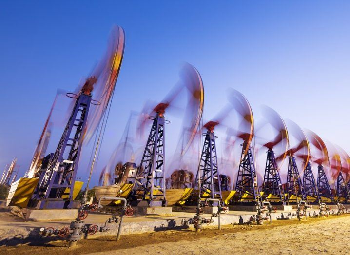 Timelapse shot of oil derricks pumping oil against a dusk background.