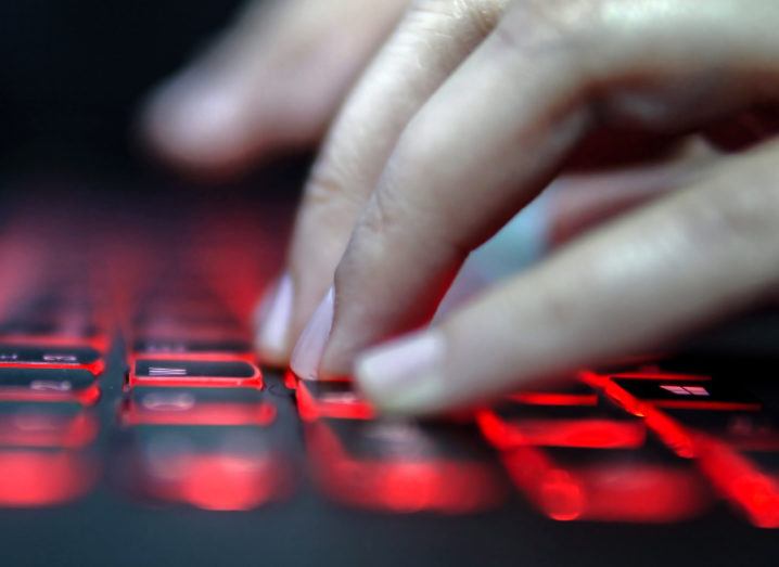 View of hands floating over keyboard backlit with red light.