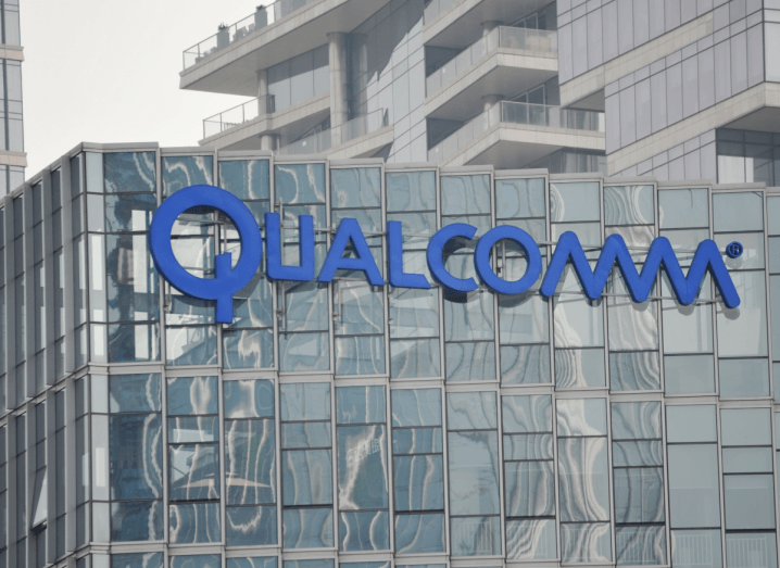 A glass building with the blue Qualcomm logo on the side of it.