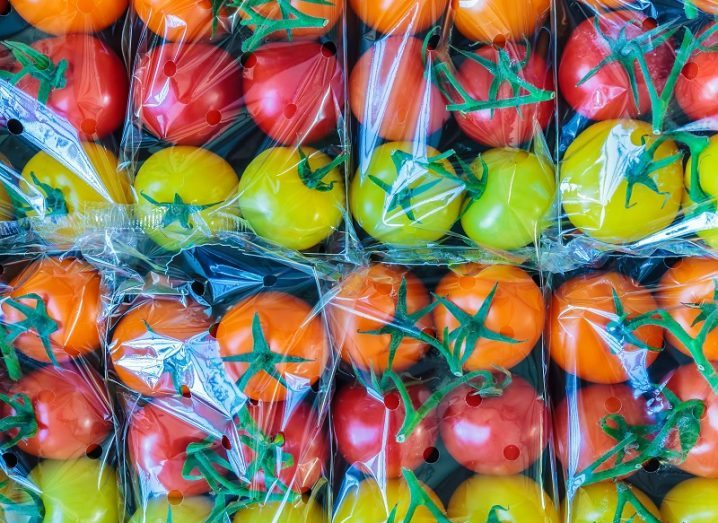 Display of yellow, orange and red tomatoes all wrapped in single-use plastics.