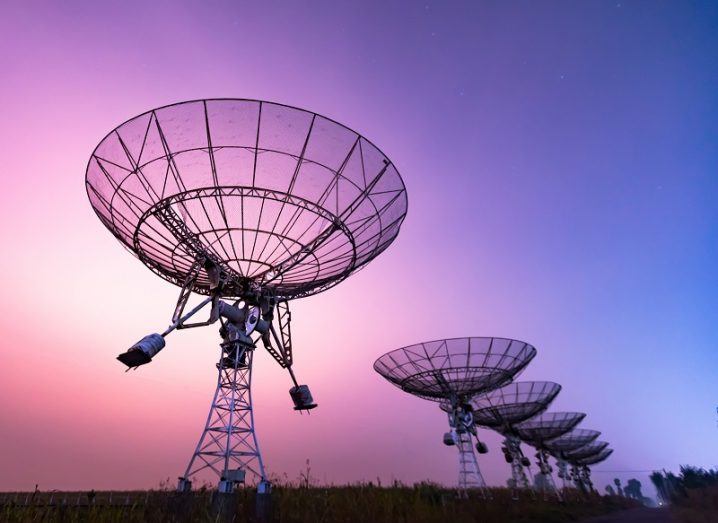 Series of radio telescopes against a purple and pink sky.