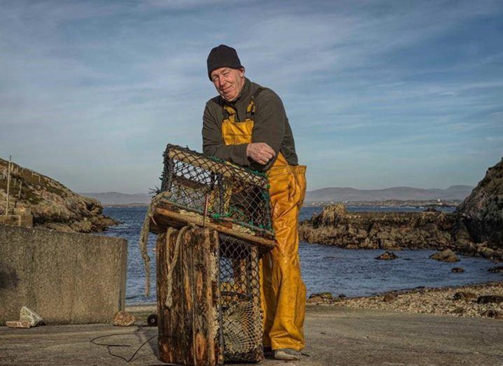 A fisherman stands leaning on a fishing cage against a scenic backdrop against the sea on Arranmore, an island off the coast of Donegal.