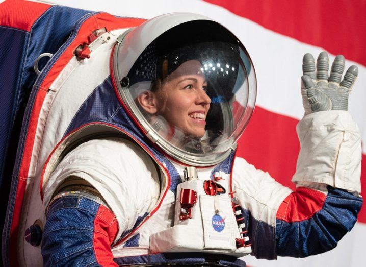 NASA spacesuit engineer Kristine Davis wearing the new spacesuit, smiling and waving.