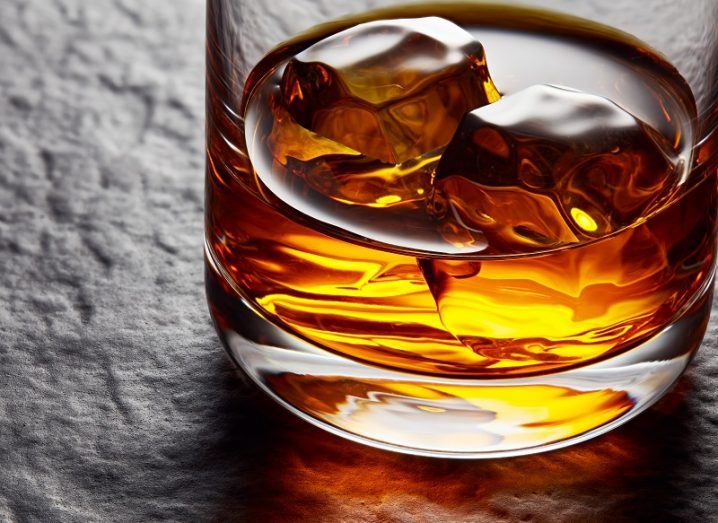 Tumbler glass filled with ice and Irish whiskey on a stone table.