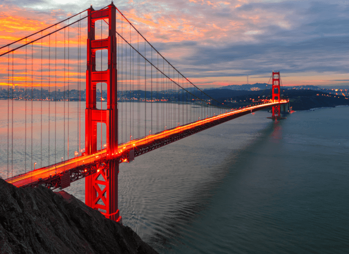 A large, red cable bridge across the San Francisco Bay Area.